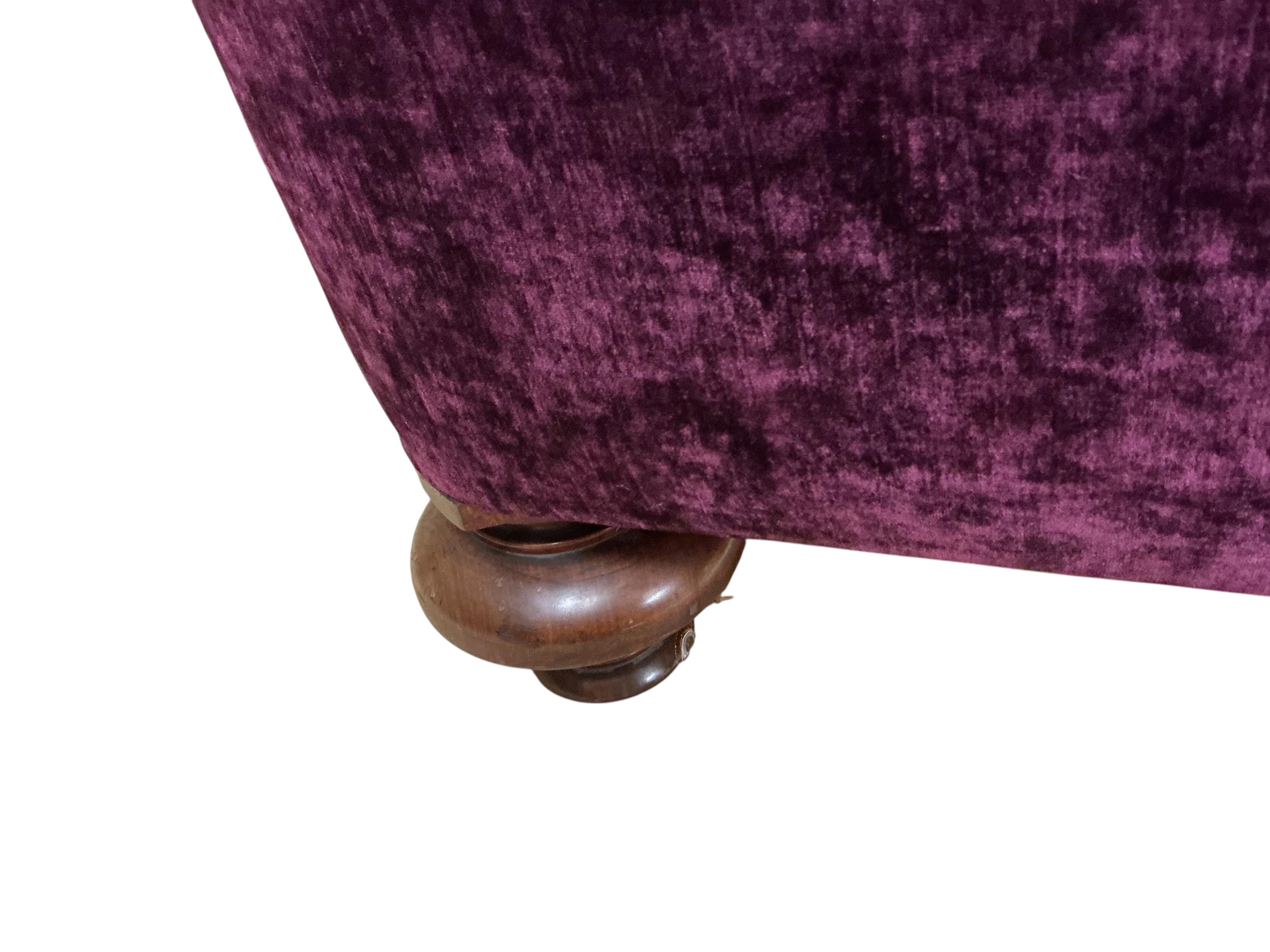 A Victorian mahogany settee upholstered in purple velvet, one rear castor detached, width 230cm, depth 84cm, height 74cm.
